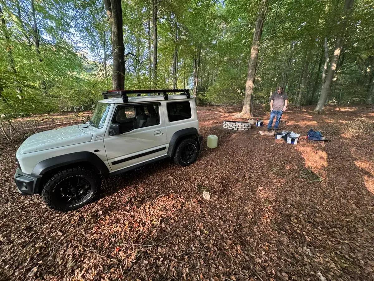 Firepit construction in progress with materials and Jimny